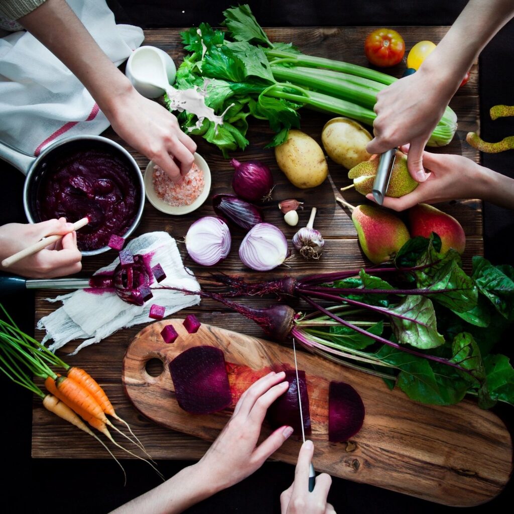 Health and Wellbeing blog is a picture of a table with healthy food and four hands reaching for different foods.